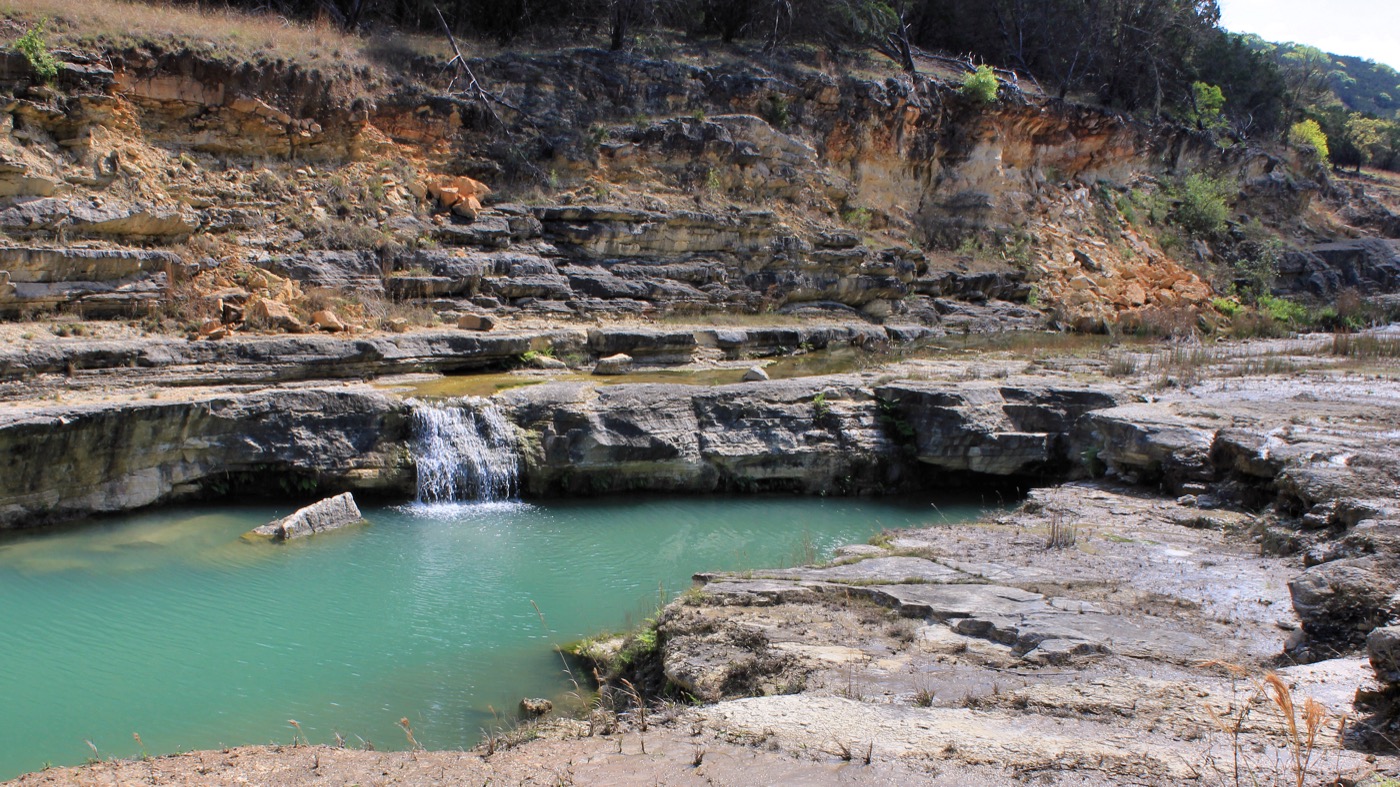 Canyon Lake Turquoise pool and small waterfall below limestone ledges in Canyon Lake Gorge